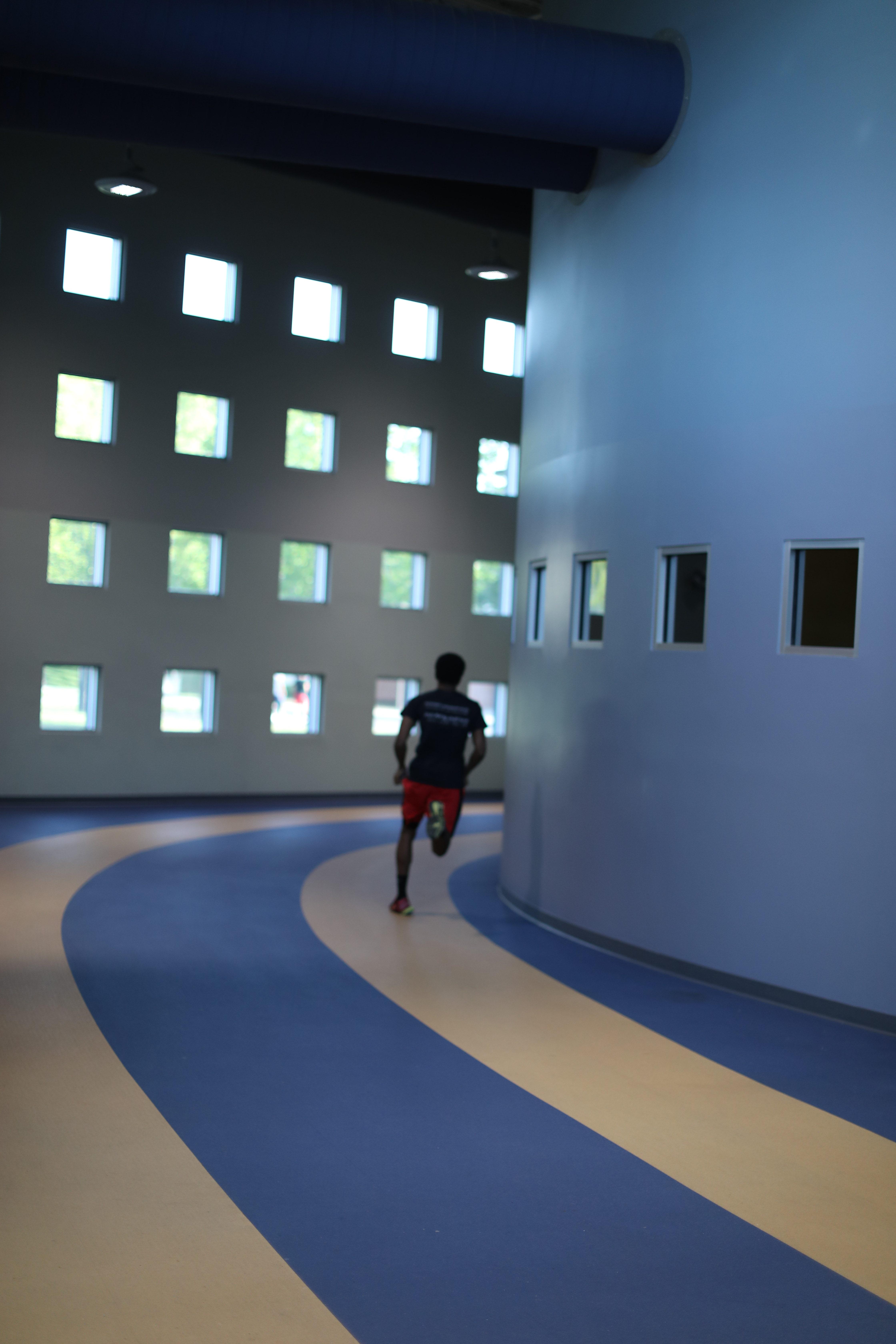  一个a和t的学生在室内跑道上跑步-校园娱乐中心